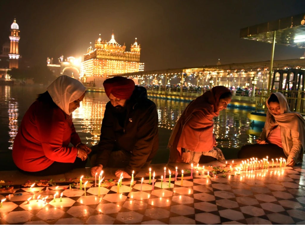 Sikh menyalakan lilin di Kuil Emas di Amritsar, India