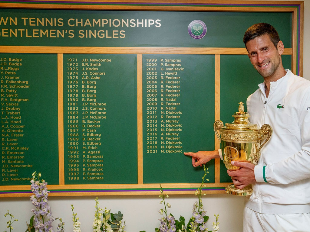 djokovic berpose di papan nama-nama juara Wimbledon