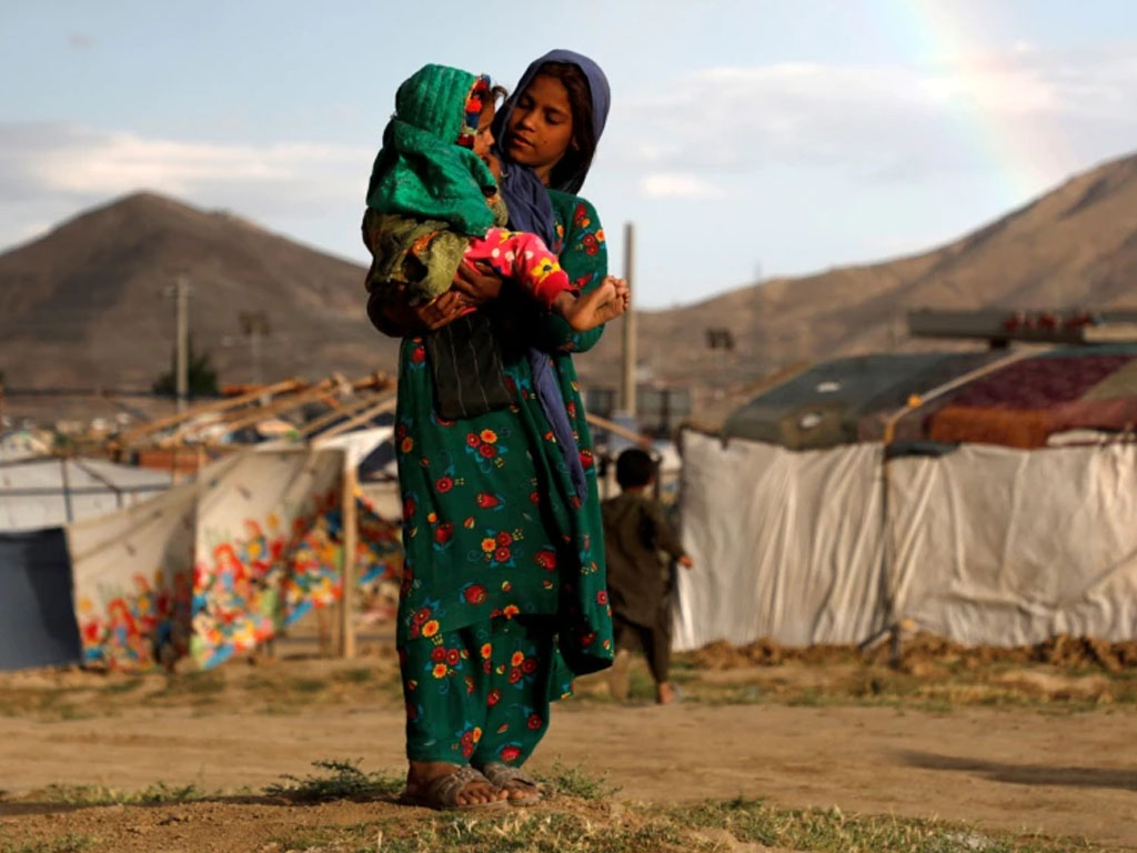 Seorang gadis pengungsi Afghanistan menggendong anak di luar kota Kabul