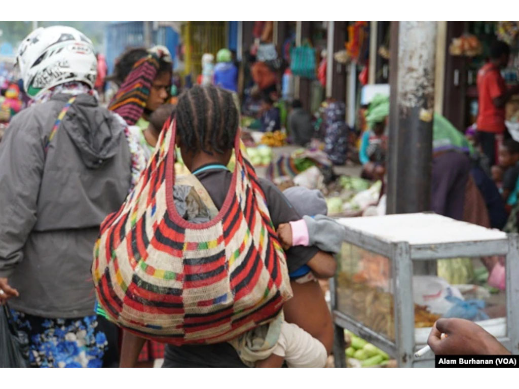 seorang ibu bawa noken di papua