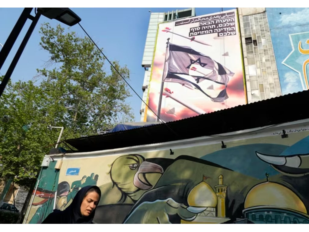 perempuan iran di depan mural anti israel di Teheran