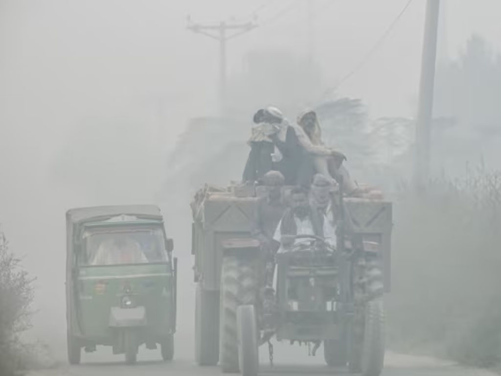 pekerja naik kendaraan di kabut asap di lahore